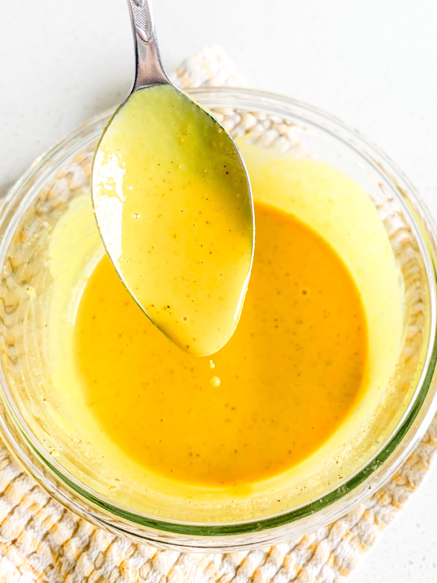 freshly made carolina gold bbq sauce being served on a spoon