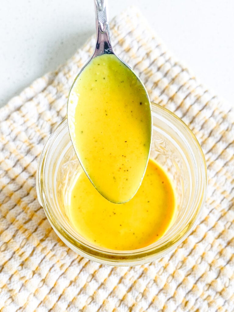 freshly made carolina gold bbq sauce being served on a spoon