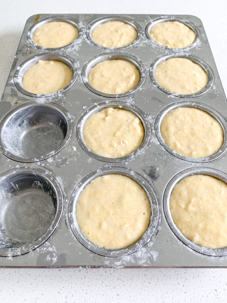 buttered and greased muffin tin filled with corn muffin batter