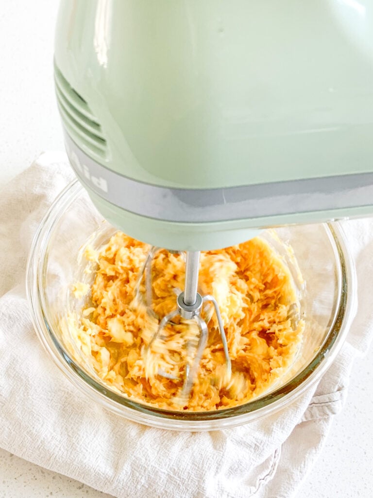 sorghum butter ingredients getting whipped together with an electric mixer in a bowl