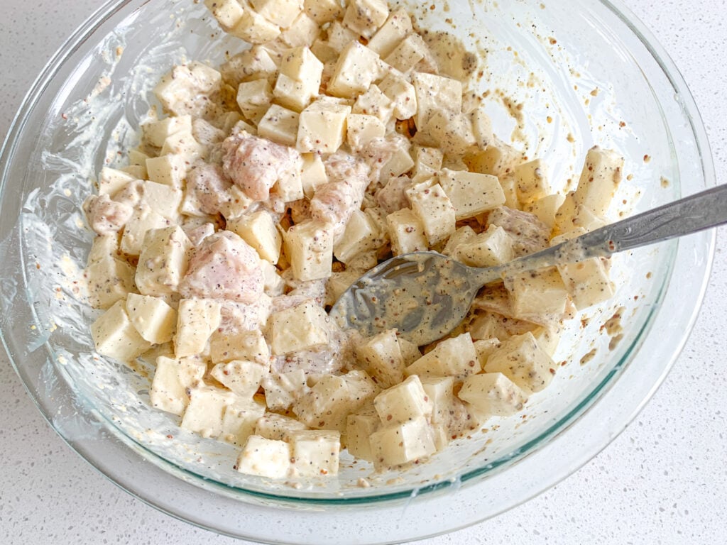mixing chicken and potatoes in zesty homemade sauce