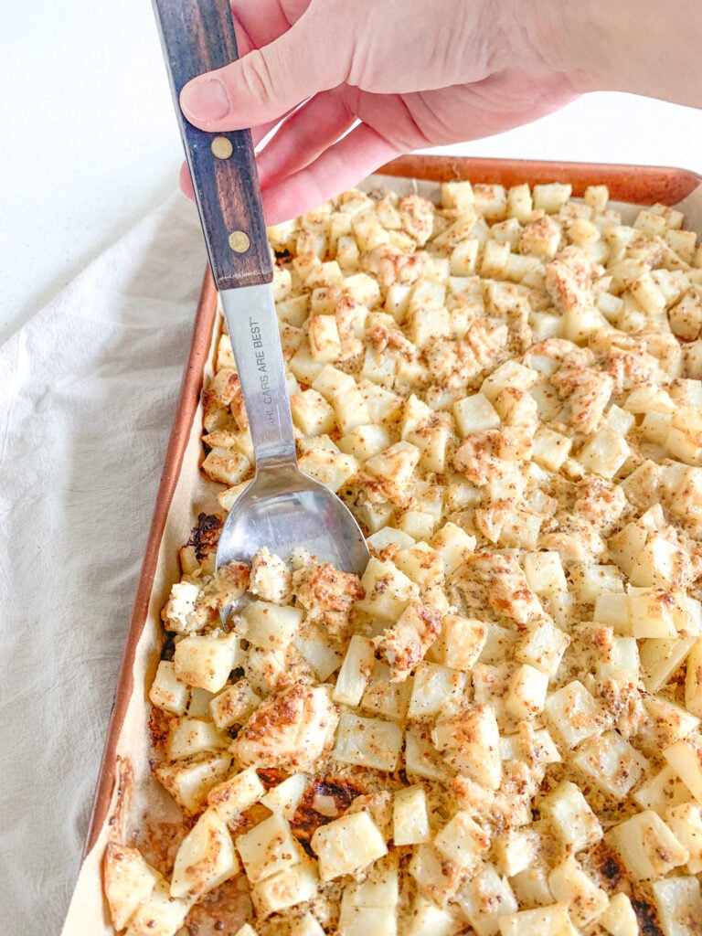 serving zesty sheet pan chicken and potatoes with a spoon