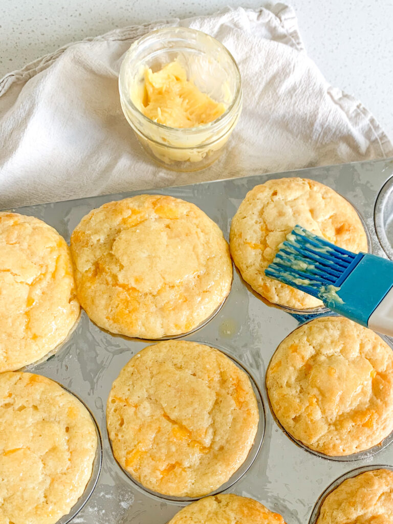 brushing sourdough muffins with honey butter