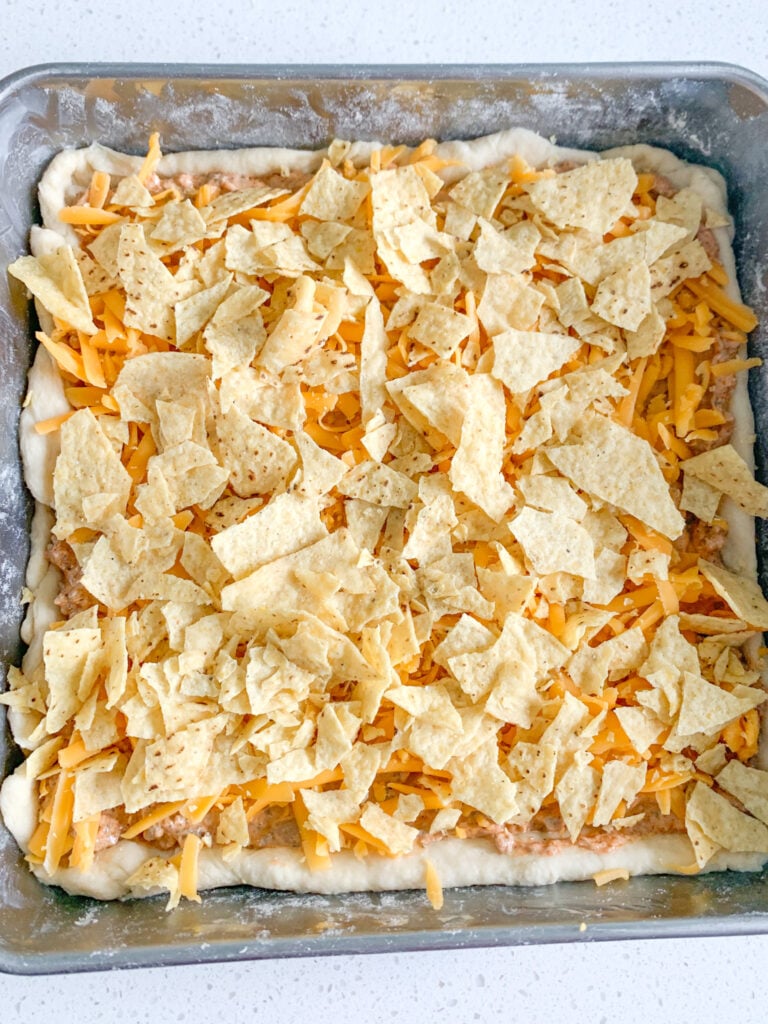 crushed tortilla chips added to the top of taco bake before baking