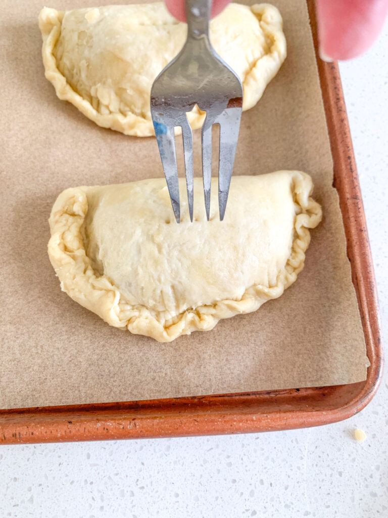 poking holes with a fork on top of sourdough hand pies before baking