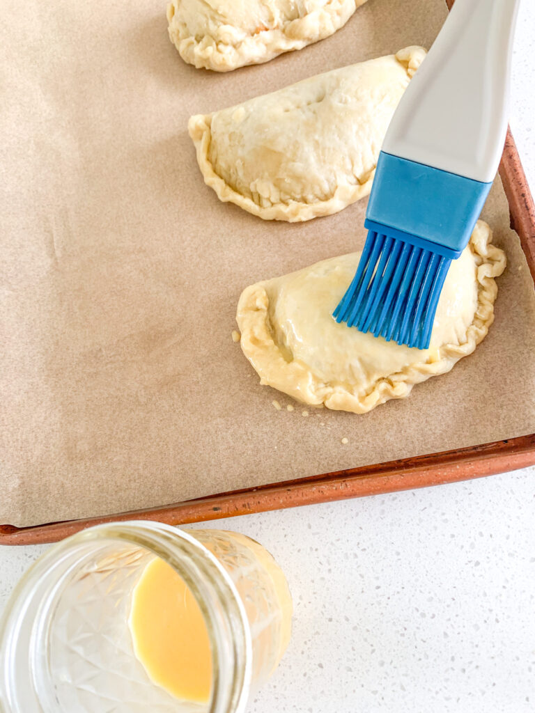 brushing sourdough hand pies with egg wash before baking
