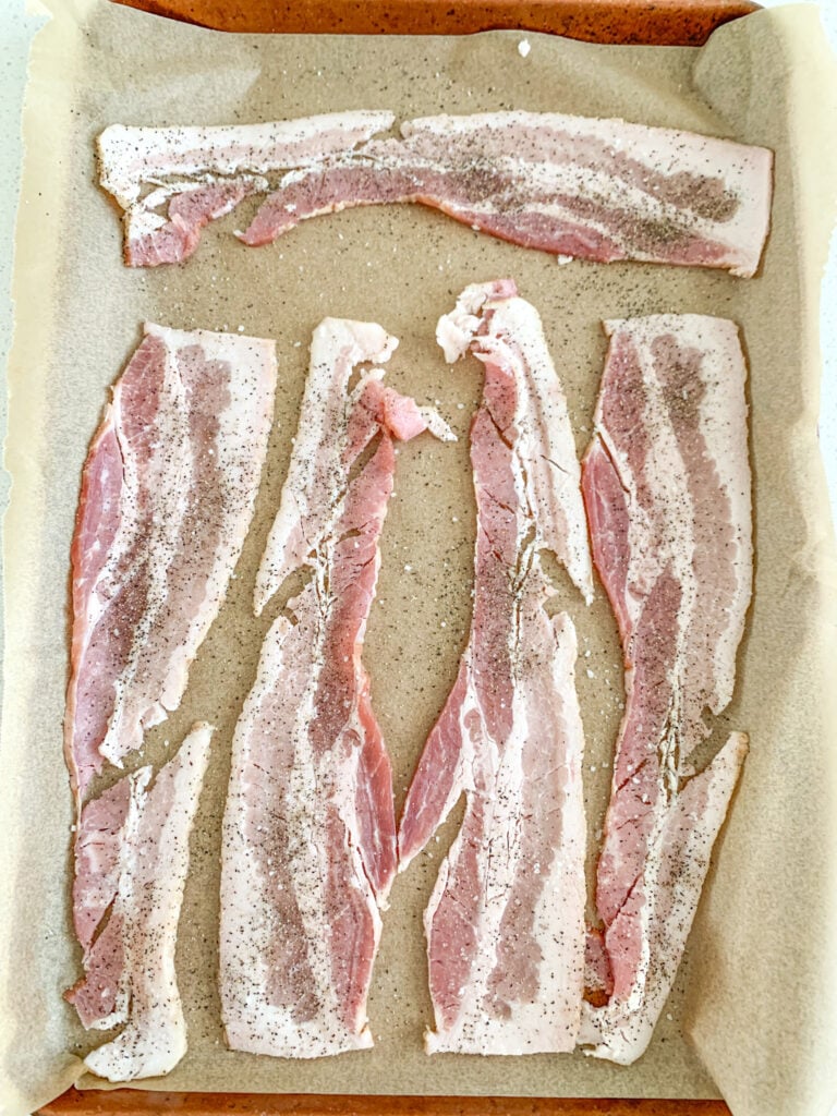 raw bacon on a sheet pan ready to bake