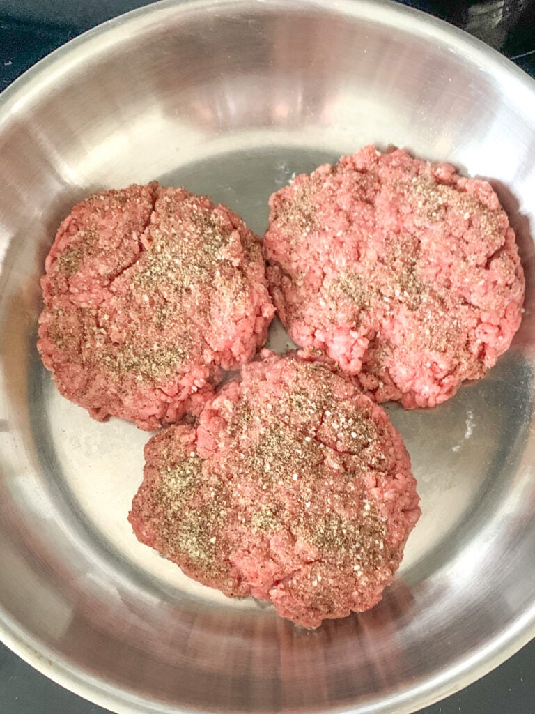 hamburger patties beginning to cook in a skillet