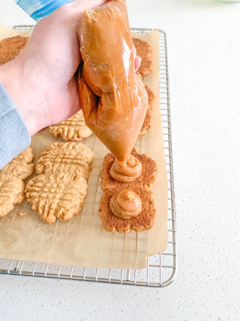piping peanut butter filling on homemade nutter butter cookies