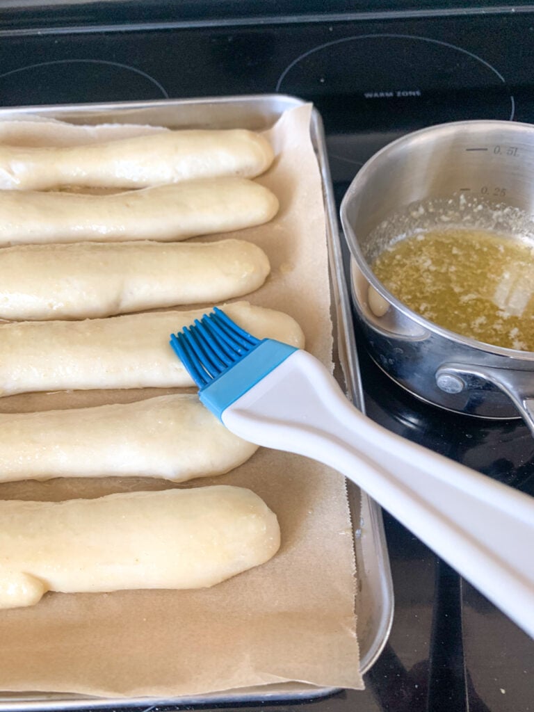 brushing risen breadsticks with garlic butter
