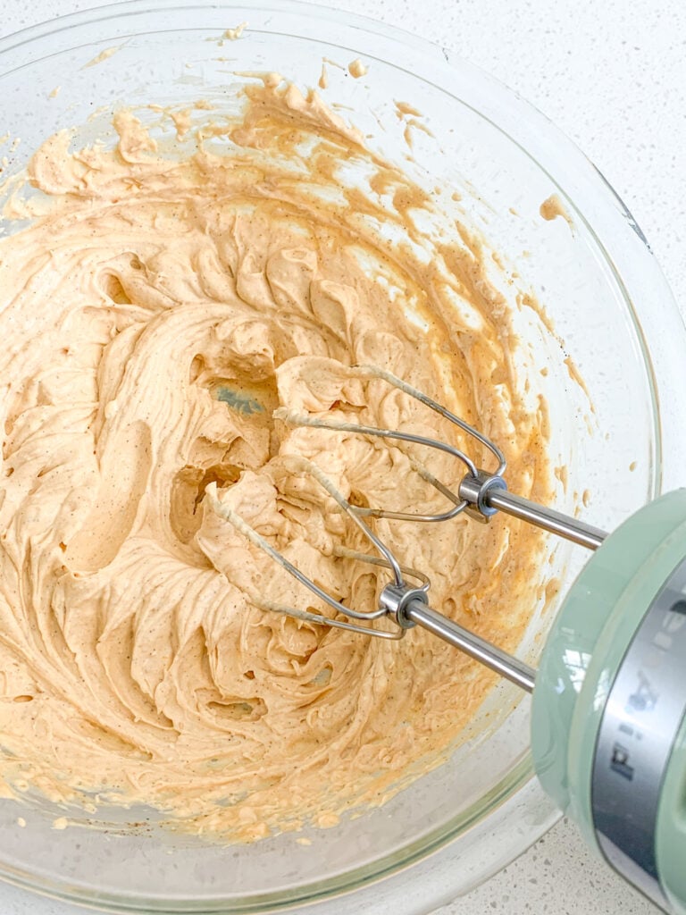 mixing together pumpkin cream cheese frosting